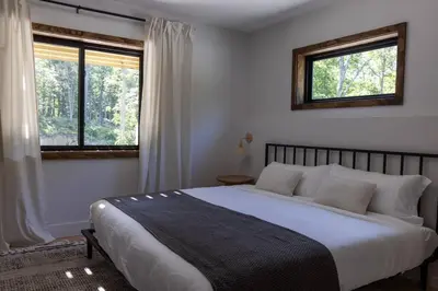 a bedroom with a large bed and two windows at Emberwood Lodge - Luxury Cabin, Kid Friendly in Catskill