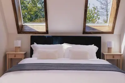 a bedroom with a large bed with two windows at Emberwood Lodge - Luxury Cabin, Kid Friendly in Catskill