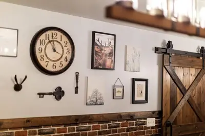 a wall with a clock and pictures on it at Harmony Hill Stylish 4bd Mountain Retreat, Hot Tub, Games in Bushkill