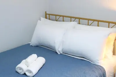 a bed with two rolled towels and a pillow at 4 bedroom short term rental furnished Apt in Schenectady
