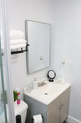 a white bathroom with a sink and a mirror at 4 bedroom short term rental furnished Apt in Schenectady
