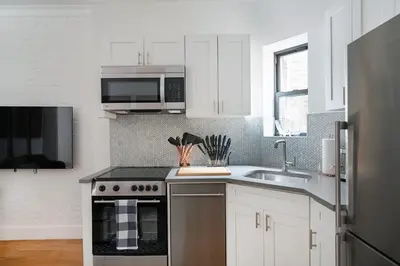 a kitchen with white cabinets and a sink and a microwave at 1290-13 Newly Renovated 2 Bedrooms in UES in New York