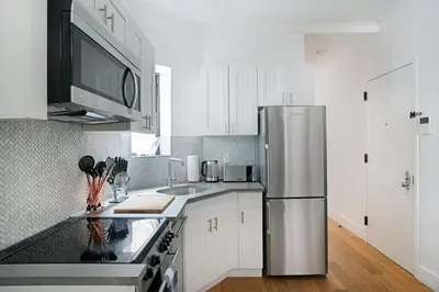 a kitchen with white cabinets and a stainless steel refrigerator at 1290-13 Newly Renovated 2 Bedrooms in UES in New York