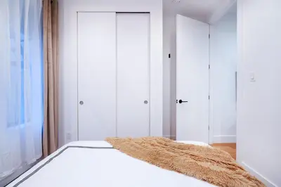 a bedroom with white walls and a bed with a rug on it at 1290-6 Newly Renovated 2 Bedrooms in UES in New York