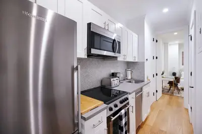 a kitchen with a stainless steel refrigerator and white cabinets at 1290-6 Newly Renovated 2 Bedrooms in UES in New York