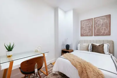 a bedroom with a desk and a bed with a white bedspread at 1290-8 New Renovated 2 Bedrooms in UES in New York