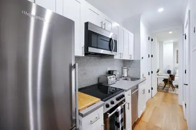 a kitchen with white cabinets and a stainless steel refrigerator at 1290-8 New Renovated 2 Bedrooms in UES in New York