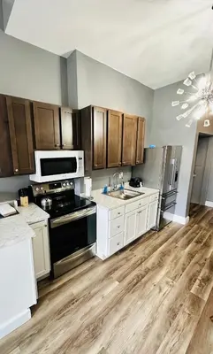 a kitchen with white cabinets and black appliances at Spacious Apartment Downtown Albany, NY in Albany