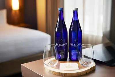 two blue bottles and two wine glasses on a table at Inn at Bellefield Residence Inn by Marriott in Hyde Park