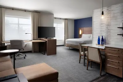 a hotel room with a bedroom and a bed and a desk at Inn at Bellefield Residence Inn by Marriott in Hyde Park