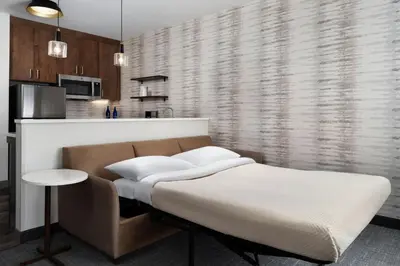 a bedroom with a bed and a couch and a kitchen at Inn at Bellefield Residence Inn by Marriott in Hyde Park