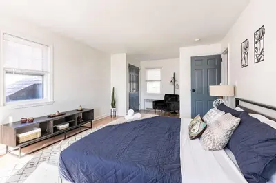 a bedroom with a blue bed and a living room at Fire pit ~ Game Room ~ near NYC ~ Modern Luxury in New Rochelle