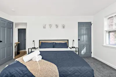 a bedroom with a large bed and two windows at Fire pit ~ Game Room ~ near NYC ~ Modern Luxury in New Rochelle