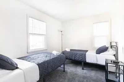 two beds in a room with two windows at Fire pit ~ Game Room ~ near NYC ~ Modern Luxury in New Rochelle