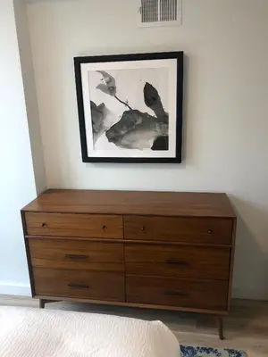 a wooden dresser in a bedroom with a picture on the wall at Modern 3BR Lofts with Outdoor Space Near NYC in Hoboken