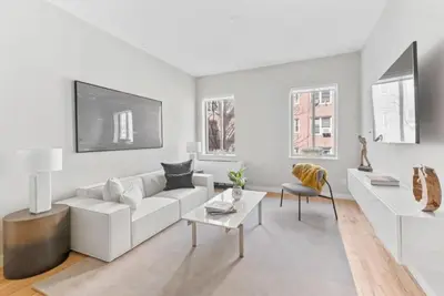 a white living room with a white couch and a table at Top Notch 2BR in Upper East Mins to Central Park in New York