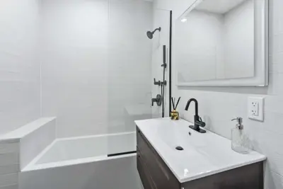 a white bathroom with a sink and a bath tub at Top Notch 2BR Suite Minutes to Central Park in New York