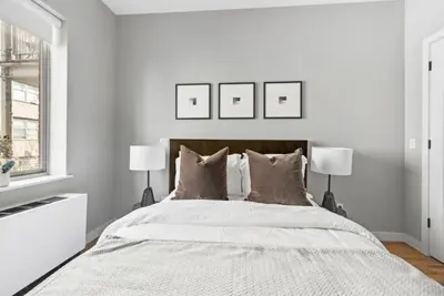 a white bedroom with a large bed with two lamps at Top Notch 2BR Suite Minutes to Central Park in New York