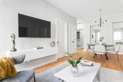 a white living room with a tv on a wall at Top Notch 2BR Suite Minutes to Central Park in New York