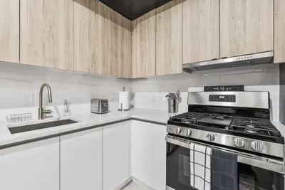 a kitchen with white cabinets and a stove top oven at Top Notch 2 Bedroom Minutes From Central Park in New York