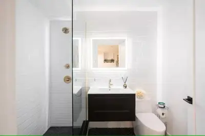 a white bathroom with a toilet and a sink at Luxury 2BR Duplex 5min to Central Park in New York