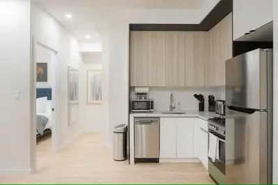 a kitchen with white cabinets and a stainless steel refrigerator at Luxury 2BR Duplex 5min to Central Park in New York