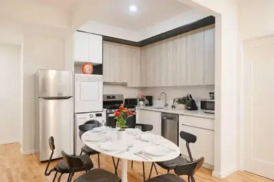 a kitchen with a table and chairs and a refrigerator at Luxury 3BR Duplex w Private Patio in Upper East in New York