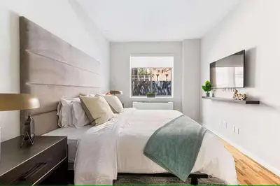 a white bedroom with a large bed and a window at Luxury 3BR Duplex w Private Patio in Upper East in New York