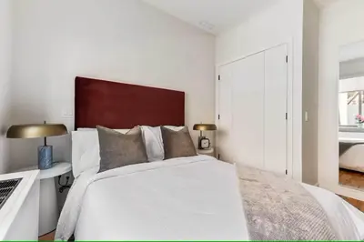 a white bedroom with a large bed and a desk at Luxury 3BR Duplex w Private Patio in Upper East in New York