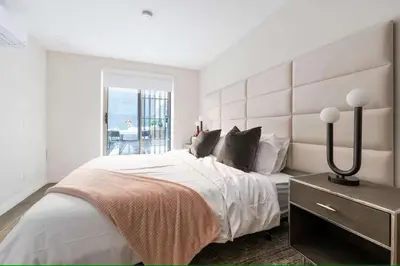 a white bedroom with a large bed and a window at Luxury 3BR Duplex w Private Patio in Upper East in New York