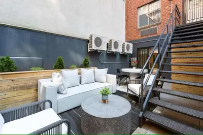 a patio with a couch and a table and stairs at Luxury 3BR Duplex w Private Patio in Upper East in New York
