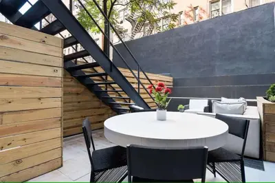 a patio with a white table and chairs and a staircase at Luxury 3BR Duplex w Private Patio in Upper East in New York