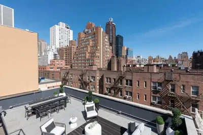 a rooftop patio with tables and chairs on a building at 3BR Penthouse with Massive Private Rooftop in New York