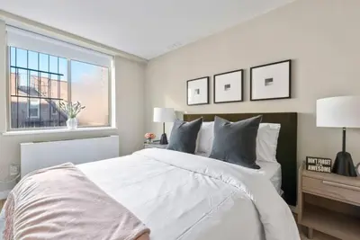 a white bedroom with a large bed and a window at 3BR Penthouse with Massive Private Rooftop in New York