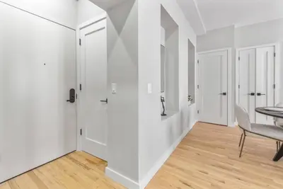 a white hallway with a table and a chair at Top Notch 2BR in Upper East Mins to Central Park in New York