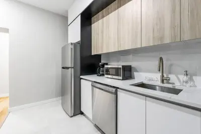 a kitchen with white cabinets and a stainless steel refrigerator at Top Notch 2BR in Upper East Mins to Central Park in New York