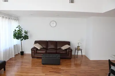a living room with a brown leather couch and a clock at Cozy & Deluxe Apartment - EZ Access to NYC in Newark