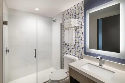 a bathroom with a toilet and a sink and a mirror at DoubleTree by Hilton Long Island City, NY in Long Island City