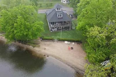an aerial view of a large house on the water at Waterfront Home on Bantam Lake with Private Beach in Morris