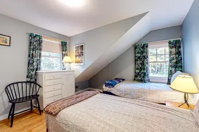 a attic bedroom with two beds and a chair at Green Mountain Retreat in Sunderland