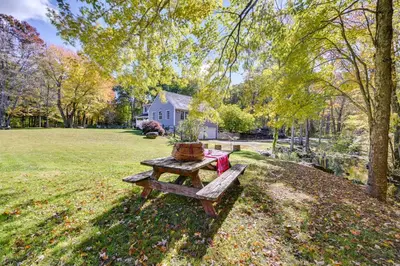 a picnic table in the grass in front of a house at Quiet Killingworth Rental with Deck and Grill! in Deep River