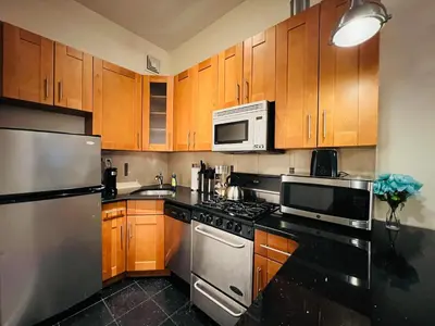 a kitchen with stainless steel appliances and wooden cabinets at Steps from Empire State Building in New York