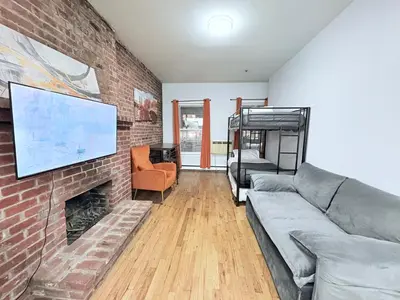 a living room with a couch and a brick fireplace at Steps from Empire State Building in New York