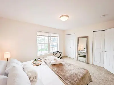 a living room with a white couch and a mirror at Luxury Stylish Townhome King Beds WD Garage in Schenectady
