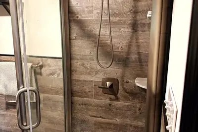 a bathroom with a shower with a wooden wall at Private estate apartment. in Glen Head