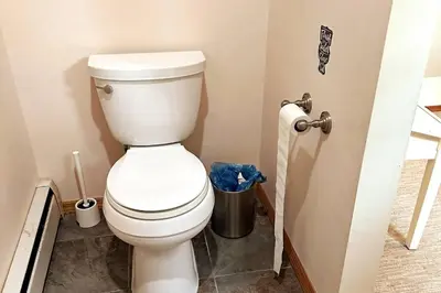 a white toilet in a bathroom with a trash can at Private estate apartment. in Glen Head