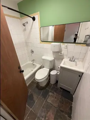 a bathroom with a toilet and a sink and a mirror at East Harlem Hostel in New York