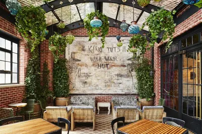 a patio with tables and chairs and a brick wall with plants at The Ludlow Hotel in New York
