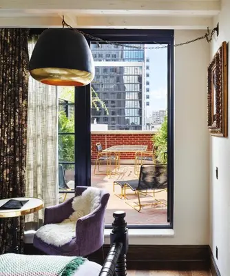 a living room with purple chairs and a large window at The Ludlow Hotel in New York