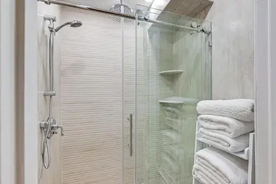 a shower with a glass door and towels in a bathroom at Walk to Harbor! Historic Mamaroneck Guest House in Mamaroneck